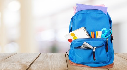 Colorful school supplies in backpack on white background