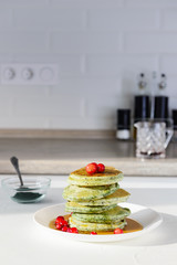 Spirulina pancakes decorated with cranberries on a white table. Healthy food concept.