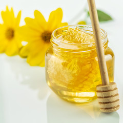 Jar with fresh floral honey on the white background. Healthy food concept.
