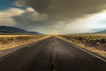 Long straight road in Utah with dramatic clouds and rain rolling in