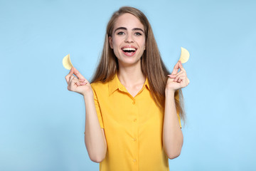 Young beautiful girl with potato chips on blue background