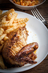 Roasted chicken with french fries on a plate.