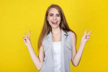 Young beautiful girl gesturing with hands on yellow background