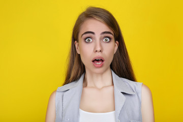 Young surprised girl on yellow background