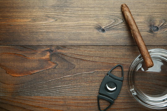cigar, ashtray and cigar guillotine on wooden background top view with copy space