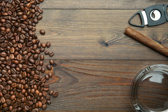 cigar, coffee beans, ashtray and cigar guillotine on wooden background with copy space