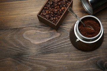 ground coffee in a coffee maker with a teaspoon on a wooden background with copy space. background with roasted coffee grains. 