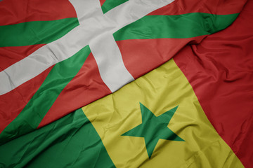 waving colorful flag of senegal and national flag of basque country.