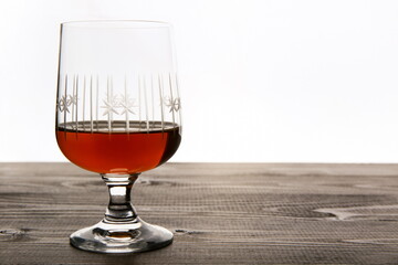 glass with dark alcohol on a wooden surface on a white background with copy space