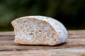 Piece of moldy bread on wooden table and dark background_