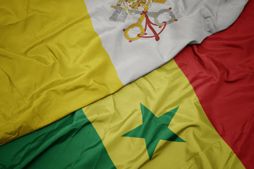 waving colorful flag of senegal and national flag of vatican city.