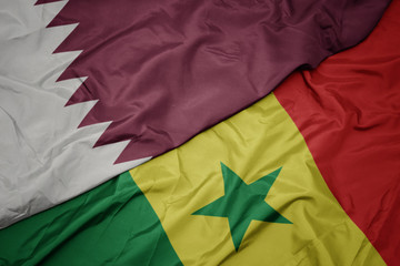 waving colorful flag of senegal and national flag of qatar.