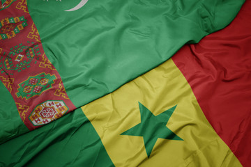Obraz premium waving colorful flag of senegal and national flag of turkmenistan.