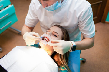 Patient with cheek retractor lies on the dental chair during the procedure  teeth whitening