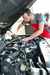 Obraz na płótnie Canvas Auto mechanic repairs vehicle in a workshop