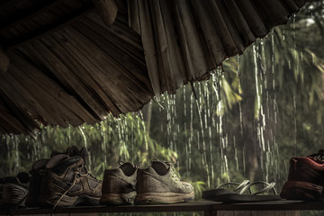 Hiking shoes in traveler shelter hut during rain in bad weather day in tropical forest