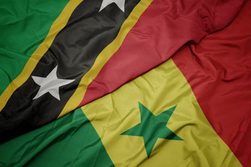 waving colorful flag of senegal and national flag of saint kitts and nevis.