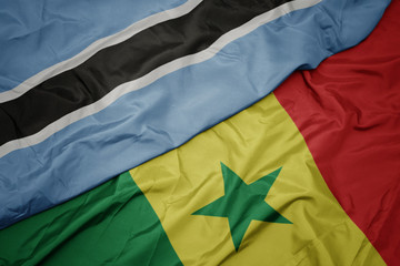 waving colorful flag of senegal and national flag of botswana.