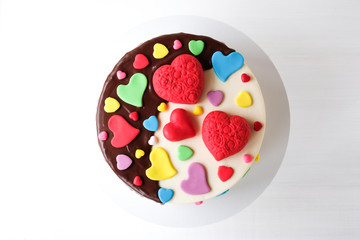 White cake decorated with colorful hearts, confectionery sprinkles and drenched in chocolate on a...