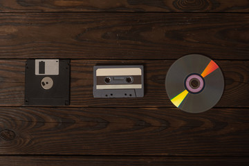 A floppy disk, cassette and cd drive are on a burnt wooden shield. concept art, the evolution of removable media