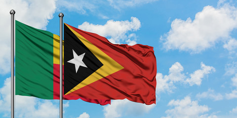Benin and East Timor flag waving in the wind against white cloudy blue sky together. Diplomacy concept, international relations.