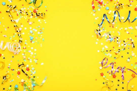 Colorful Ribbons With Paper Stars And Confetti On Yellow Background