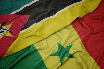 waving colorful flag of senegal and national flag of mozambique.