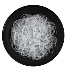 Cellophane or glass noodles in black matte plate isolated on a white background, top view