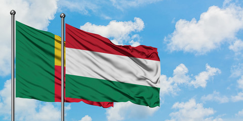 Benin and Hungary flag waving in the wind against white cloudy blue sky together. Diplomacy concept, international relations.