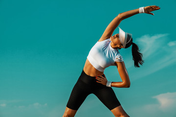 Individual sports recreation. Sporty and fit young woman athlete doing yoga training on the sky background. The concept of a healthy lifestyle and sport.