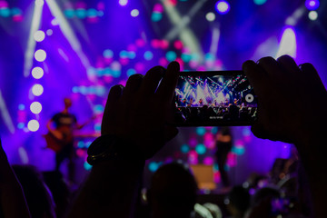 Fototapeta na wymiar smart phone on the hand during a live concert with toned special effect