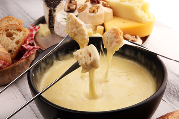 Gourmet Swiss fondue dinner on a winter evening with assorted cheeses on a board alongside a heated...