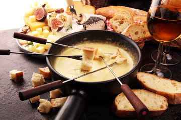 Gourmet Swiss fondue dinner on a winter evening with assorted cheeses on a board alongside a heated...