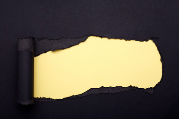 Hole in the black paper. Torn. Yellow paper background. Abstract background.