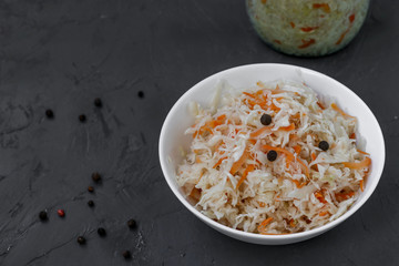Homemade Sauerkraut with carrots in a bowl on a dark background, Fermented food, closeup