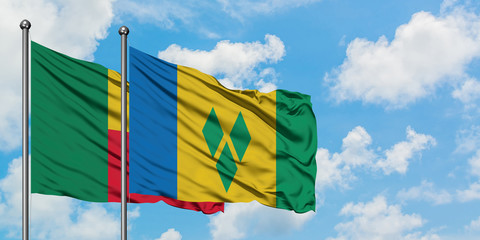 Benin and Saint Vincent And The Grenadines flag waving in the wind against white cloudy blue sky...