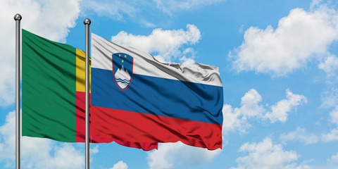 Benin and Slovenia flag waving in the wind against white cloudy blue sky together. Diplomacy concept, international relations.