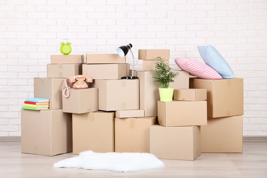 Cardboard boxes with household stuff on brick wall background