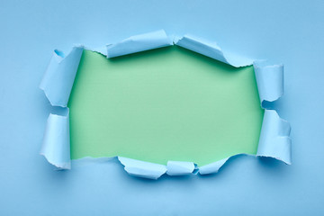 Hole in the blue paper. Torn. Green background. Abstract background.