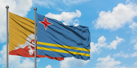 Bhutan and Aruba flag waving in the wind against white cloudy blue sky together. Diplomacy concept, international relations.