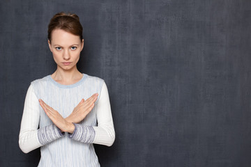 Portrait of serious focused girl showing stop gesture with hands