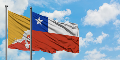 Bhutan and Chile flag waving in the wind against white cloudy blue sky together. Diplomacy concept, international relations.