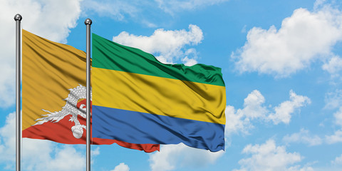 Bhutan and Gabon flag waving in the wind against white cloudy blue sky together. Diplomacy concept, international relations.