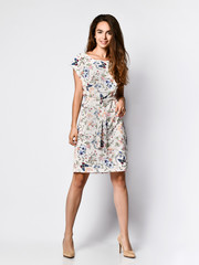 Fototapeta premium Slim curly female model in a silk pale dress looking at the camera in full growth. Cute girl in romantic clothes is going on a date