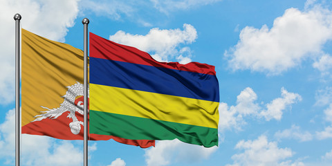 Bhutan and Mauritius flag waving in the wind against white cloudy blue sky together. Diplomacy concept, international relations.