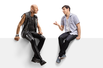 Young man talking to a punk in leather clotes and sitting on a panel