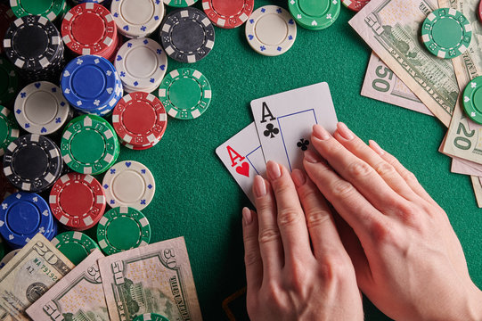 A player in a poker casino shows a pair of aces against the background of chips and money of dollars. Victory, success. Gaming business.