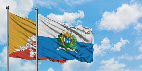 Bhutan and San Marino flag waving in the wind against white cloudy blue sky together. Diplomacy...
