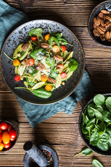 Vegetarian pasta salad with spinach, red and orange tomato, capers and pecan nuts, topped with shredded cheese