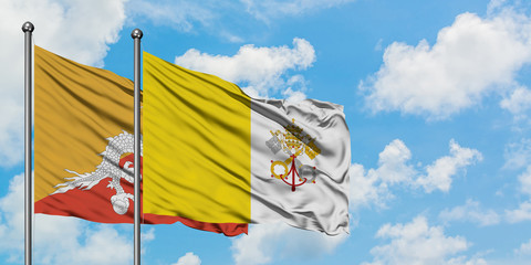Bhutan and Vatican City flag waving in the wind against white cloudy blue sky together. Diplomacy...